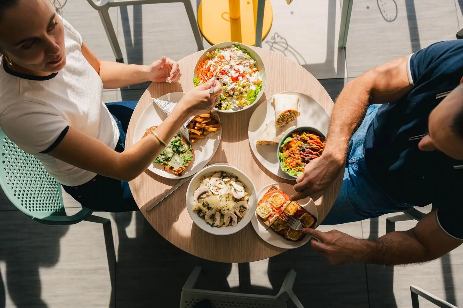 Un bowl garni, des wraps et des frites posés sur une table en bois