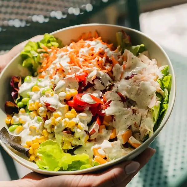 Un bowl garni tenu à bout de bras, prêt à partir