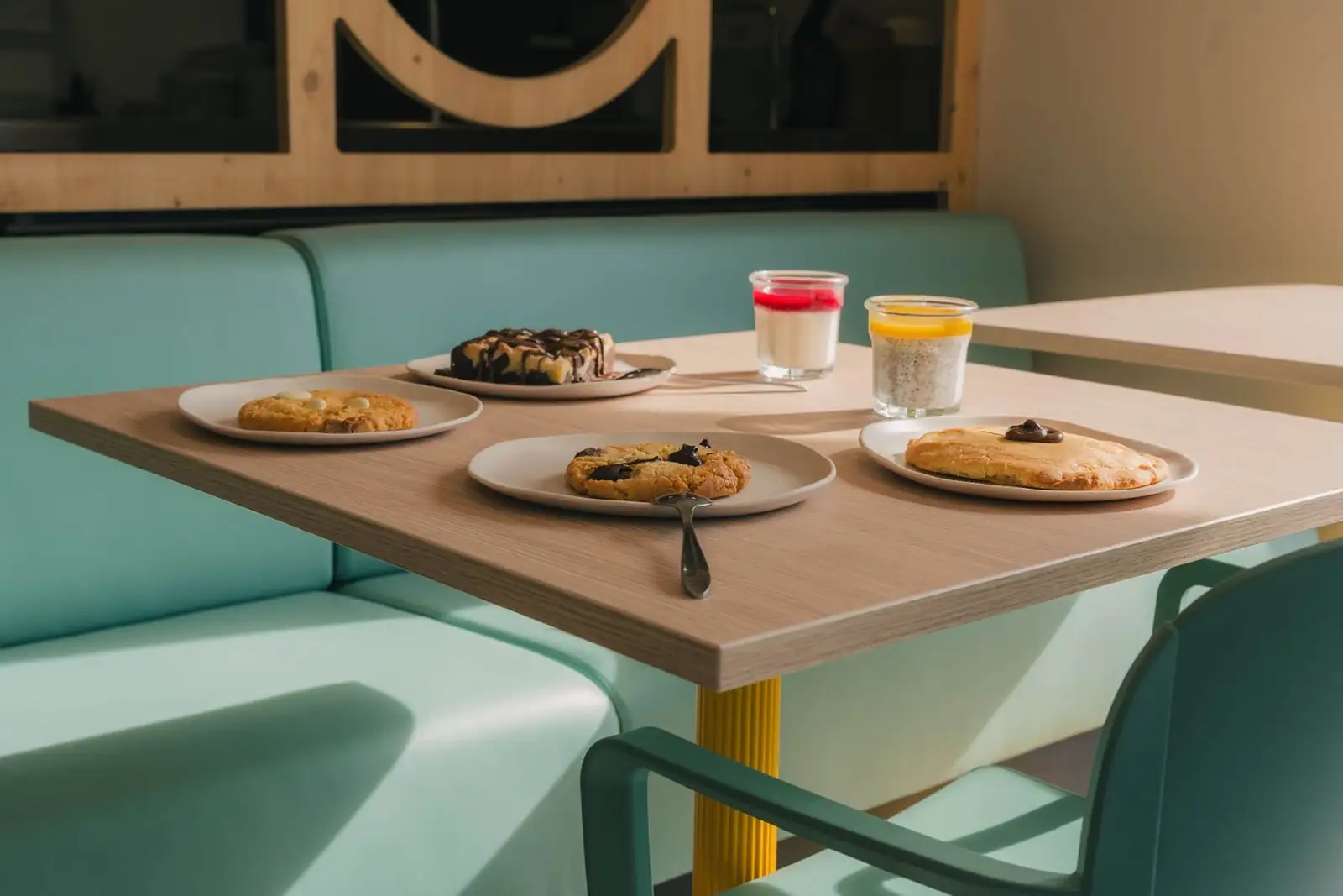 Une table du restaurant, cookies et desserts devant la banquette vert d’eau